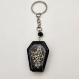 Coffin shaker keychain filled with oil and floating charms.