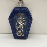 Coffin shaker keychain filled with oil and floating charms.