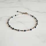 Adjustable blue and gunmetal anklet with a chain.