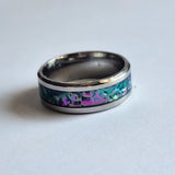 Hand-turned dichroic resin ring on a stainless steel band, shifting purple, blue, and green in the light.
