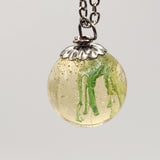 Suspended ink resin pendant on silver stainless steel chain.