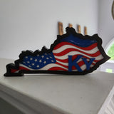 A decorative plaque in the shape of Kentucky with the American flag colors and the letter 'KY' on it, made of wood and resin