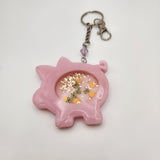 Piggybank shaker keychain filled with oil and floating charms.