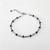 Adjustable silver ankle bracelet with a chain and purple  beads.